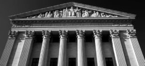 photo of a building front with many pillars, atop the pillars is a triangular relief with a carving of several figures