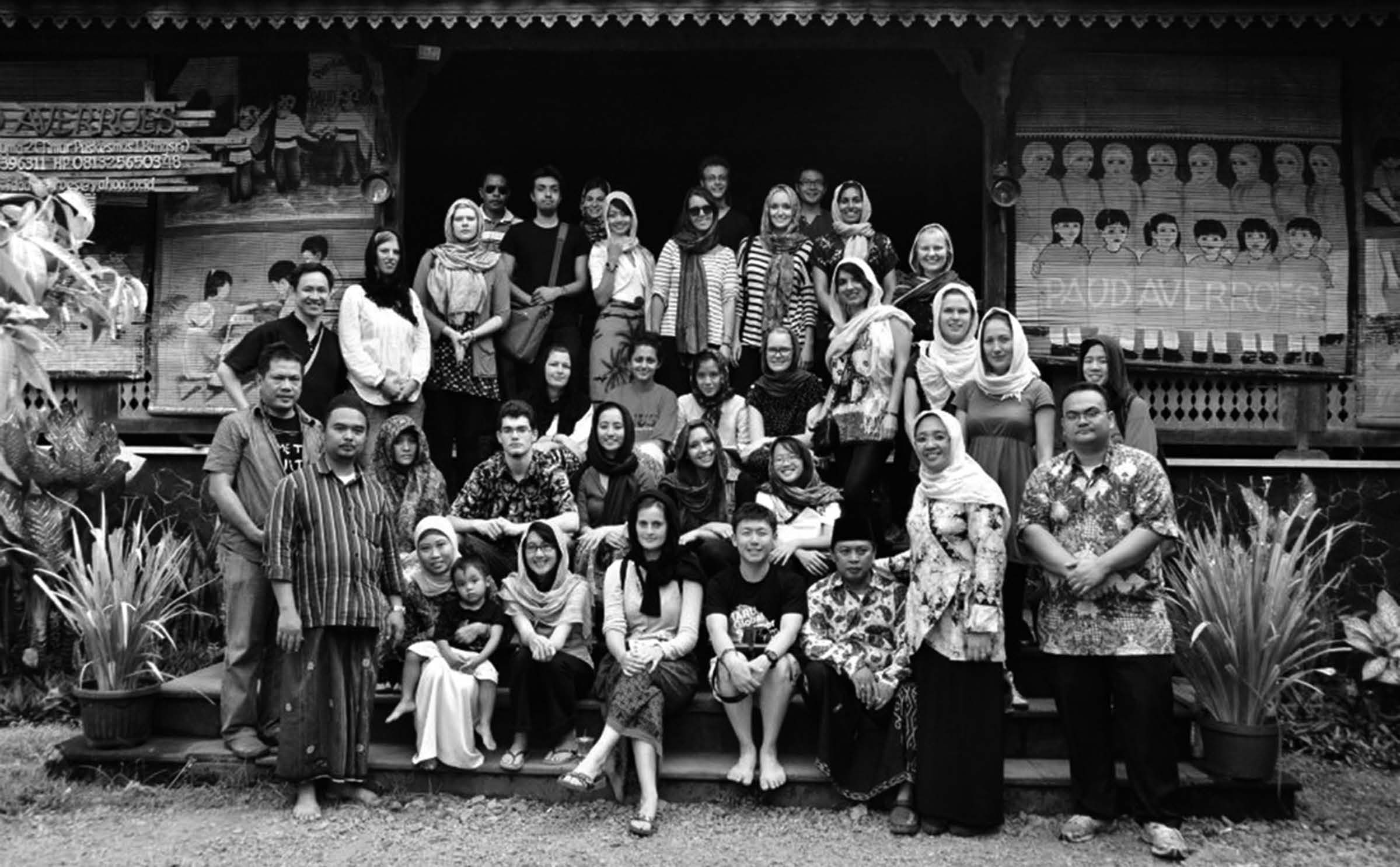 A group photo of students sitting and standing in rows in front of a Islamic boarding school in Indonesia. 