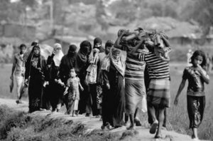 photograph of people walking, carrying various materials and packs.