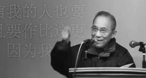 an old man speaks into a microphone in front of chinese text