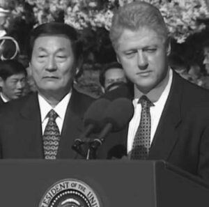 two middle aged men in suits stand behind a podium and microphone