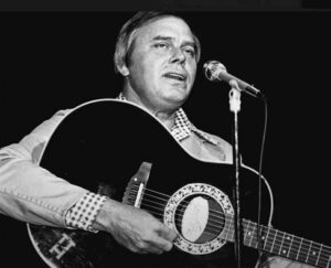 a black and white photo of a man singing into a microphone while playing guitar