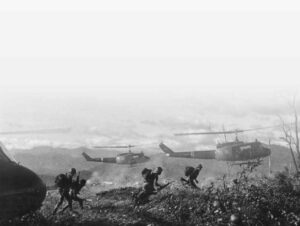 black and white photo of men jumping from helicopters and running in tall grass