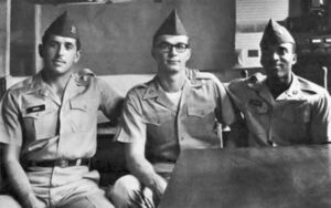 three men in military uniforms sit with arms around each other