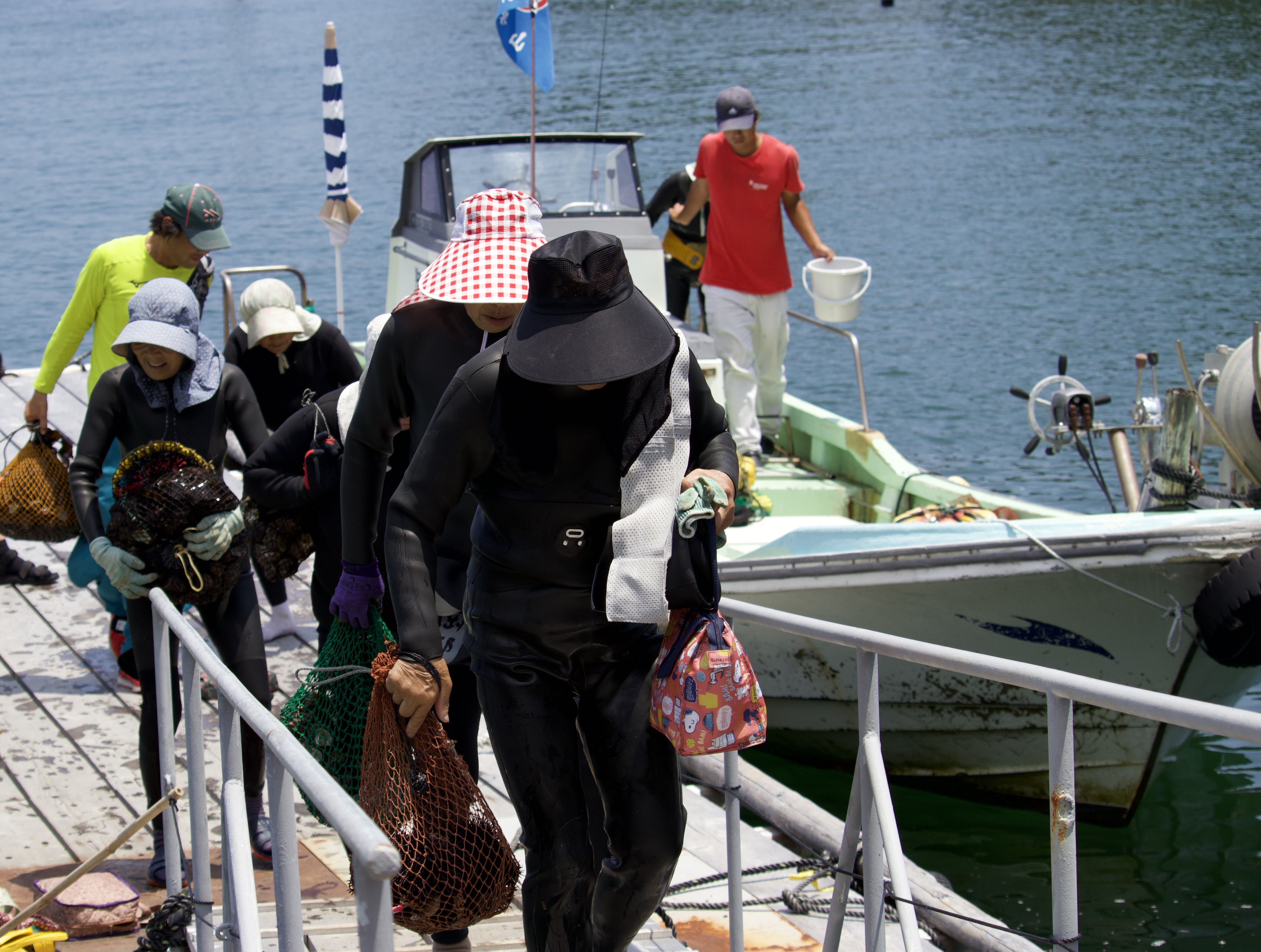 Ama return from a day of diving with net bags full of shellfish.