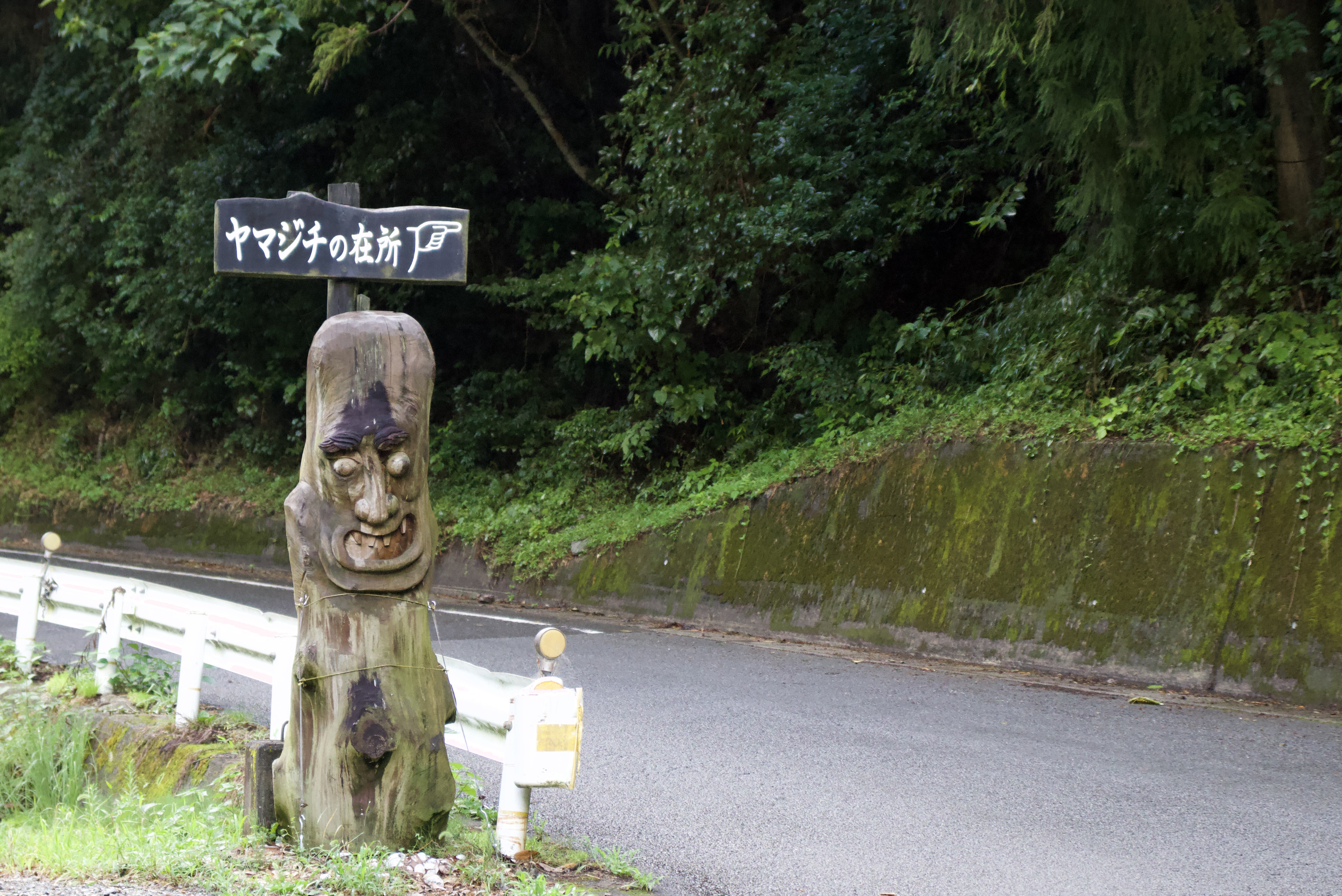 A wooden statue and sign indicating where the yamajichi legend occurred.