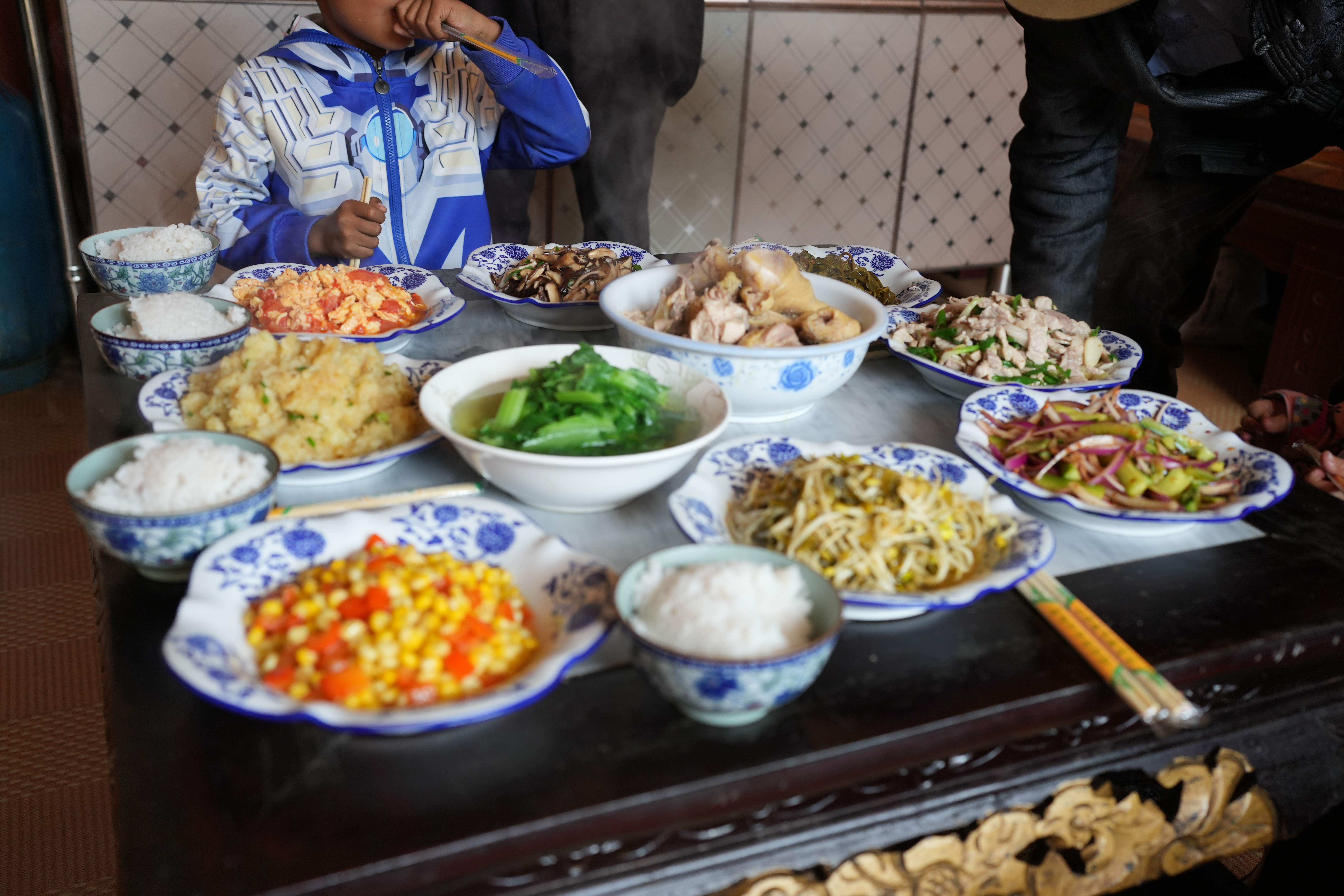  Mosuo dining table laden with chicken soup and vegetable dishes.
