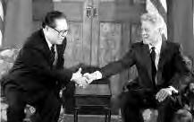 two middle aged men in suits shake hands