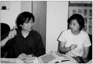 A male flipping through a book is talking to a woman
