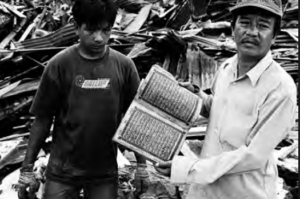 Image shows two men holding a book in the ruins of house
