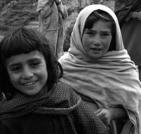 two children, a boy and a girl. the girl wearing a headcovering.